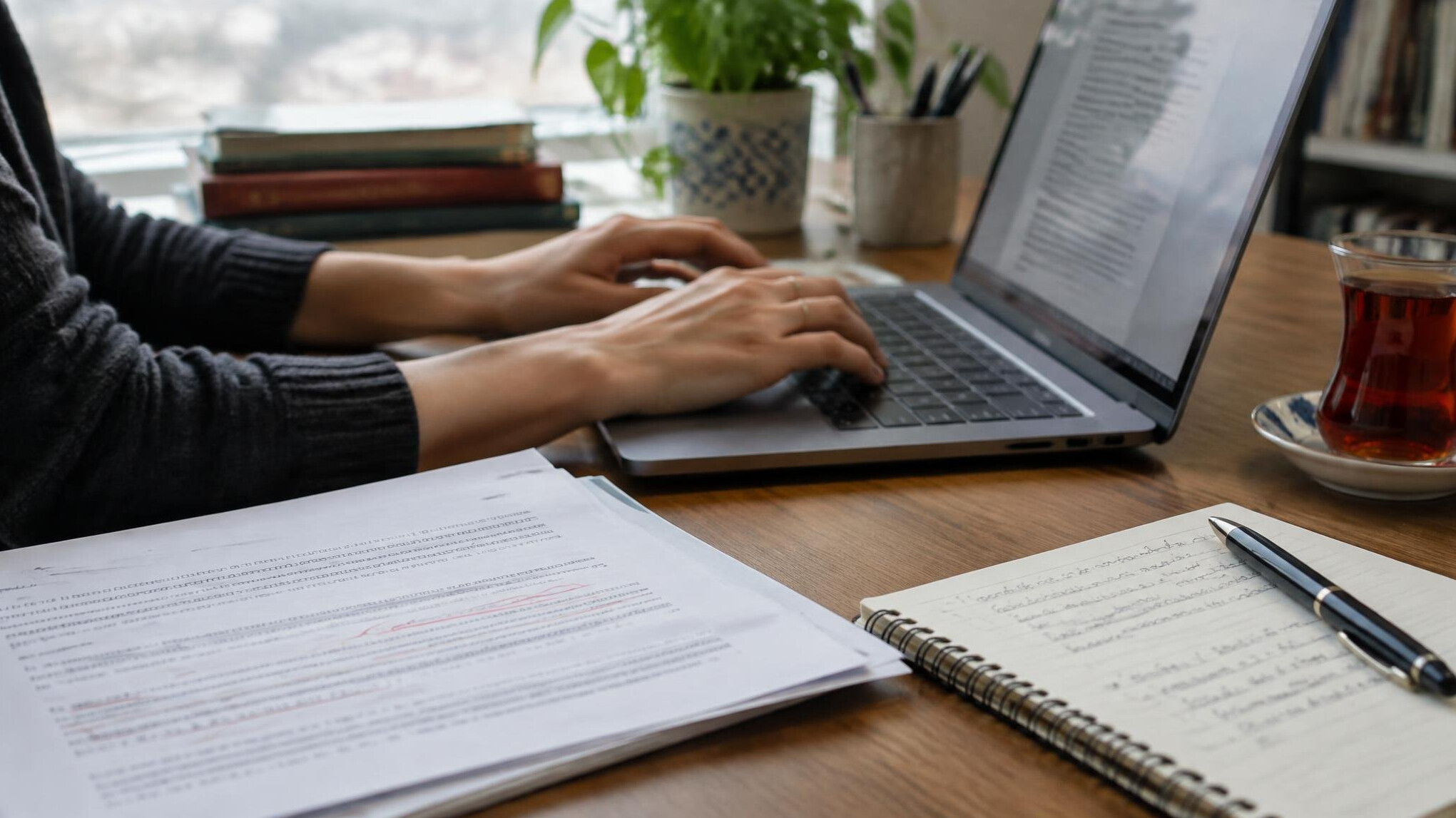 Editor reviewing documents and a laptop at a desk